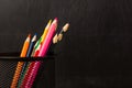 Black pencil holder full of colorful pencils, isolated over school blackboard background Royalty Free Stock Photo