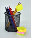 Black pencil holder with pencils and pens, with sticky notes on the front on a white surface Royalty Free Stock Photo