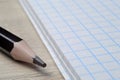 a black pencil lies on the table next to an open notebook. close-up. Royalty Free Stock Photo