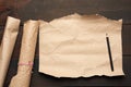 Black pencil and roll of untwisted brown paper on a wooden surface from old boards Royalty Free Stock Photo