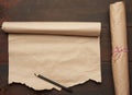 Black pencil and roll of untwisted brown paper on a wooden surface from old boards Royalty Free Stock Photo