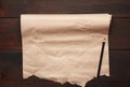 Black pencil and roll of untwisted brown paper on a wooden surface from old boards Royalty Free Stock Photo