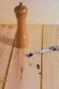 Black pepper grains and pepper grinder close up on wooden neutral background Royalty Free Stock Photo