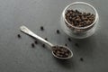 Black pepper peas on a dark background of stone, a silver spoon. Close-up Royalty Free Stock Photo