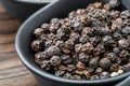 Black pepper, peppercorns in black bowl close up