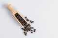 Black pepper peppercorns in wooden scoop isolated on white background Royalty Free Stock Photo