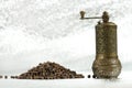 Black pepper and vintage mill on silver background. Spice grinder and heap of grains of pepper. Sample for packing