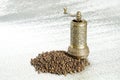 Black pepper and vintage mill on silver background. Spice grinder and heap of grains of pepper. Sample for packing Royalty Free Stock Photo