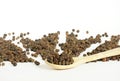 Black pepper and wooden spoon on white background. Spoon in front of heap of grains of pepper. Sample for Spice packing