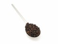 Black peppercorns on a silver spoon