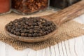 Black peppercorns in a wooden box and an old wooden table.