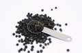 Black peppers in teaspoon on white background