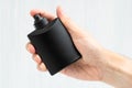 Black perfume bottle in man hand