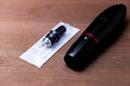 Black permanent tattoo pen with disposable cartridge on wooden table