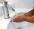 Black person washing hands with soap under running water