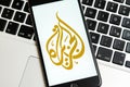 Black phone with logo of news media Al Jazeera on the screen. Royalty Free Stock Photo