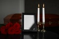 Black photo frame with burning candles and red roses on table Royalty Free Stock Photo