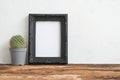 Black photo frame on old wooden table with cactus over white con Royalty Free Stock Photo