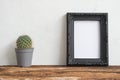 Black photo frame on old wooden table with cactus over white con