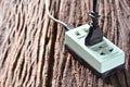 Black pin plug and green plug socket for electricity use in house on brown bark Royalty Free Stock Photo