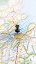 A black pin stuck in Edinburgh on a map of Scotland portrait