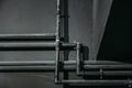Black pipes on dark wall background as abstract industrial pipeline texture
