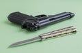 Black pistol and iron knife on a light green background Royalty Free Stock Photo