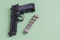 Black pistol and iron knife on a light green background Royalty Free Stock Photo