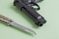 Black pistol and iron knife on a light green background Royalty Free Stock Photo