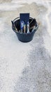 Black plastic bucket containing tools: paintbrushes, trowels, brush. Royalty Free Stock Photo