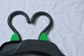 Black plastic clothes hanger arranging heart shape on white fabric background Royalty Free Stock Photo