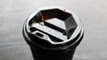 Black plastic coffee cup cover, top view. Takeaway coffee cup black background. Disposable cup close-up on a wooden table. Royalty Free Stock Photo