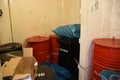 Black plastic containers and red metal drums as garbage bins inside superstructure.