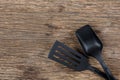 Black plastic kitchen set skimmer, spade of frying pan on wooden