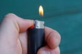 Black plastic lighter with fire holds fingers in hand Royalty Free Stock Photo