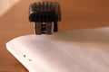 Black plastic stapler piercing papers closeup - Image