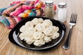 Black plate with boiled dumpling, napkin, salt, pepper and fork