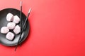 Black plate with delicious mochi and chopsticks on red background., top view. Space for text Royalty Free Stock Photo