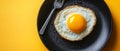 A black plate features a creative egg with a yolk, complemented by cutlery, all displayed on a light orange pastel Royalty Free Stock Photo