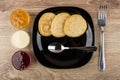 Black plate with pancakes and spoon, bowls with jam