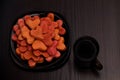 Black plate with red heart-shaped cookies and a mug of tea on a black table, Valentine's Day. Top view Royalty Free Stock Photo