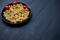 Black plate with ripe and juicy cherry tomatoes and different types of raw pasta