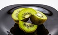 Black plate with several sliced kiwis against a dark background Royalty Free Stock Photo