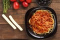 Black plate with spaghetti with sauce on a wooden table. Royalty Free Stock Photo