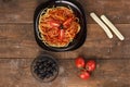 Black plate with spaghetti with sauce on a wooden table. Royalty Free Stock Photo