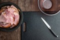 Black plate stacked with holiday ham, black cutting board, kitchen knife, glass bowl Royalty Free Stock Photo