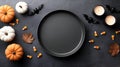 Black plate surrounded by orange and white pumpkins, candy corn, bats, and candles on a dark textured surface, creating a festive Royalty Free Stock Photo