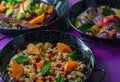 Black plate of sweet breakfast of bulgur porridge with pomegranate, peach and fruits with mint.