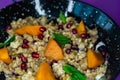 Black plate of sweet breakfast of bulgur porridge with pomegranate, peach and fruits with mint.