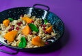 Black plate of sweet breakfast of bulgur porridge with pomegranate, peach and fruits with mint.